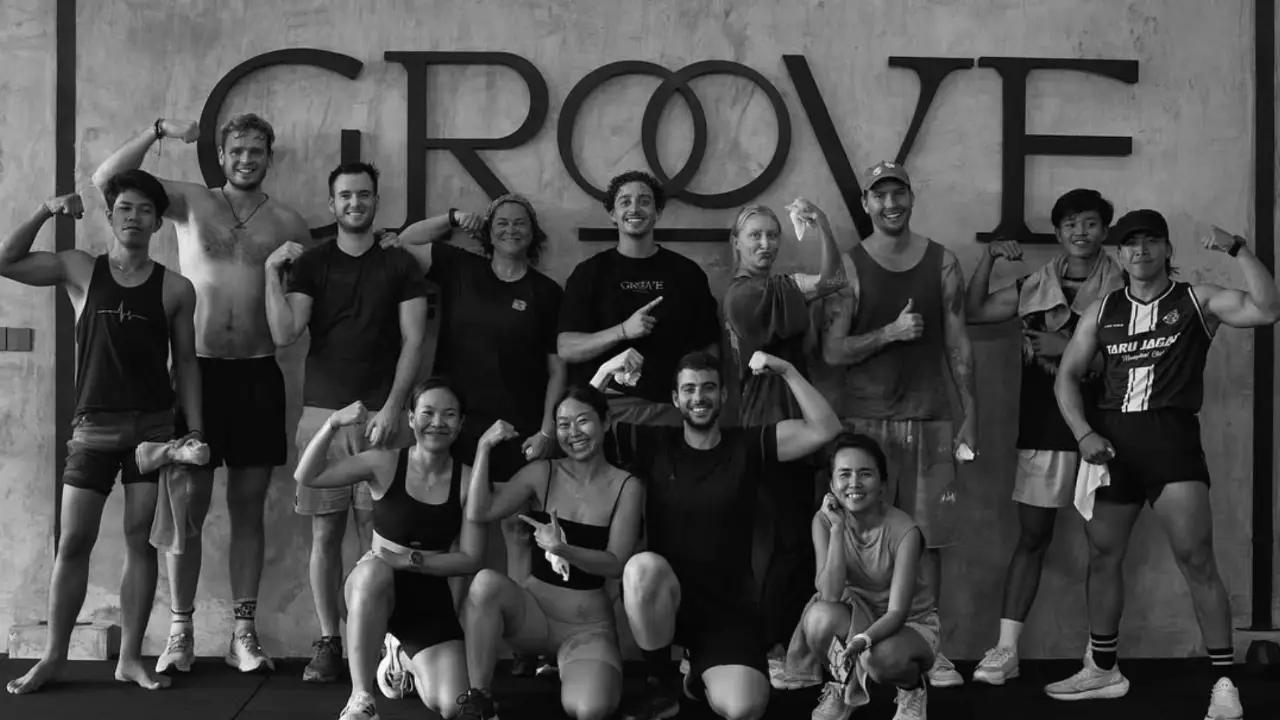 A black-and-white group photo of members flexing in front of the Groove Fitness sign at the gym in Sumberkima, north Bali