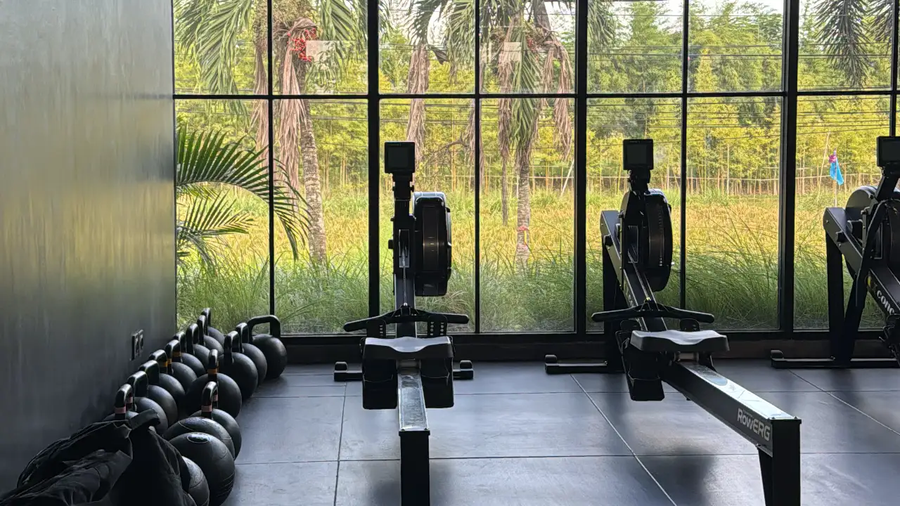 A weights floor at a gym in Bali, with racks and dumbbells under an open roof
